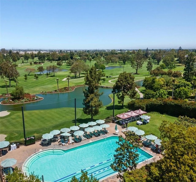 community pool with view of golf course, a lawn, a water view, and a patio