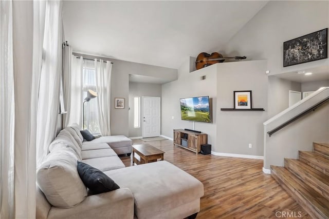 living room featuring visible vents, high vaulted ceiling, wood finished floors, baseboards, and stairs