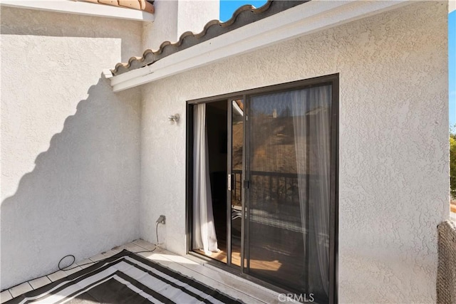 property entrance with a tile roof and stucco siding