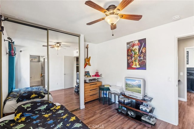 bedroom with a ceiling fan, wood finished floors, and baseboards