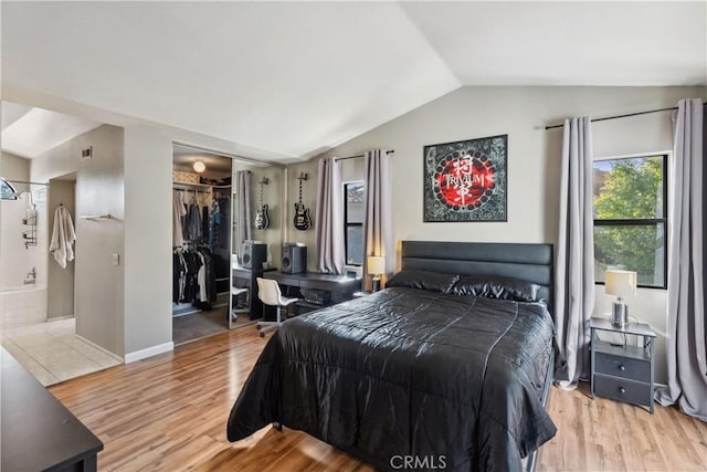 bedroom featuring vaulted ceiling, wood finished floors, a closet, and baseboards