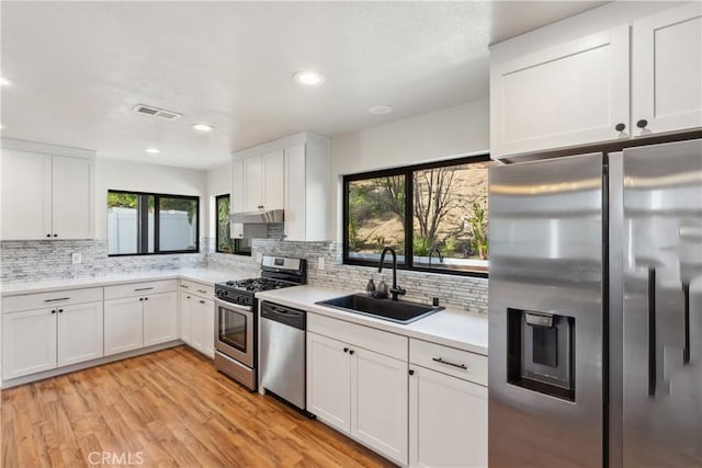 kitchen featuring visible vents, a sink, light countertops, light wood-style floors, and appliances with stainless steel finishes