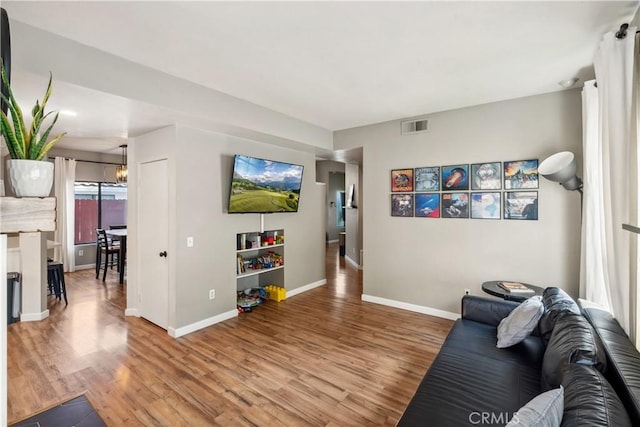 living room with light wood-style floors, visible vents, and baseboards