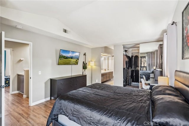 bedroom featuring baseboards, visible vents, light wood-style flooring, vaulted ceiling, and a closet