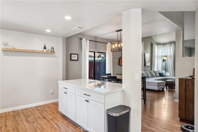 kitchen with light wood-style flooring, white cabinetry, a healthy amount of sunlight, and an inviting chandelier