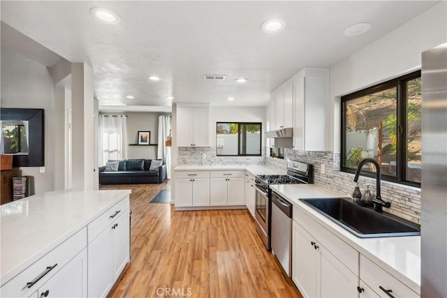 kitchen featuring a sink, visible vents, light wood-type flooring, and white cabinetry