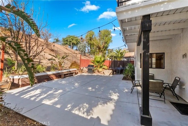 view of patio / terrace with outdoor dining area, a trampoline, a fenced backyard, and a grill