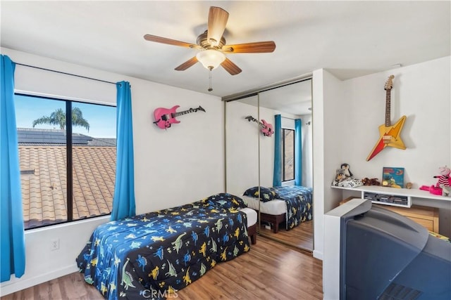 bedroom featuring a closet, baseboards, a ceiling fan, and wood finished floors