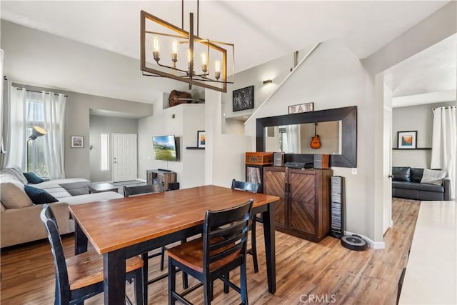 dining space featuring light wood finished floors, baseboards, and an inviting chandelier