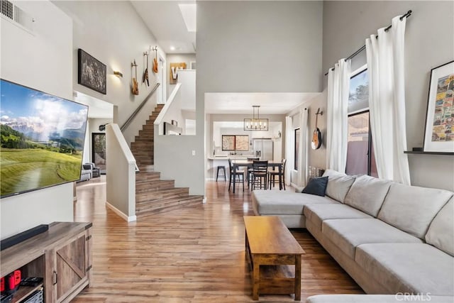 living area featuring light wood-type flooring, stairway, a high ceiling, and visible vents