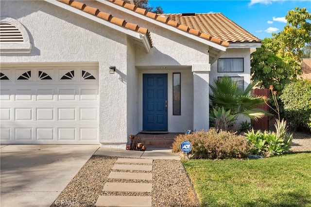 property entrance with a tiled roof, a garage, and stucco siding