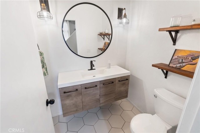 half bathroom featuring toilet, vanity, and baseboards