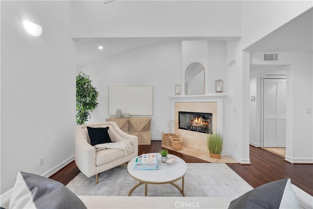 living room featuring baseboards, wood finished floors, visible vents, and a tile fireplace