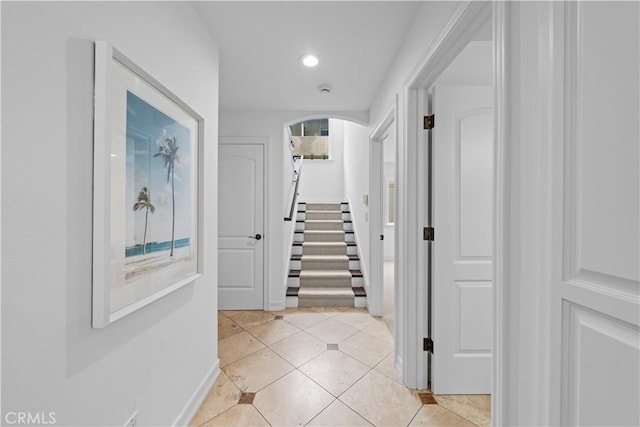 hallway with stairway, light tile patterned floors, recessed lighting, and arched walkways