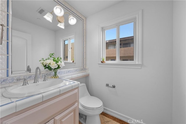 bathroom featuring vanity, visible vents, baseboards, tile patterned flooring, and toilet