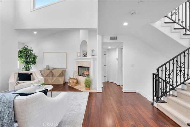 living room with visible vents, a tiled fireplace, dark wood finished floors, recessed lighting, and stairs