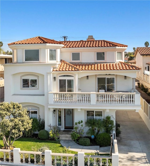 mediterranean / spanish-style home with stucco siding, concrete driveway, a tile roof, and a balcony