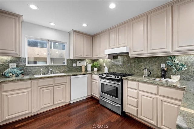 kitchen with under cabinet range hood, a sink, stainless steel range with gas cooktop, white dishwasher, and dark wood-style flooring