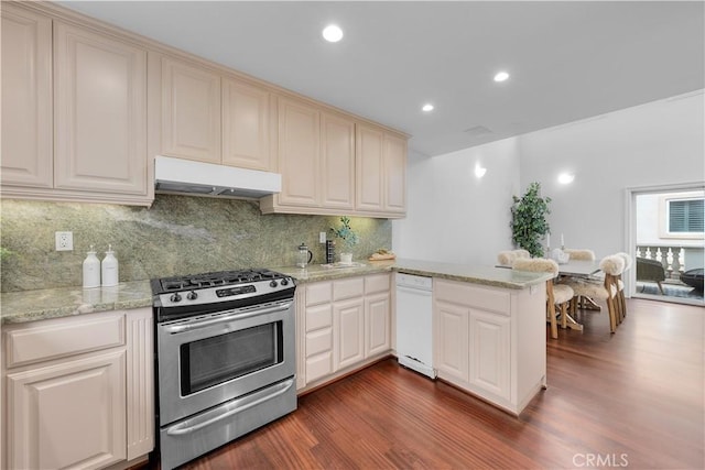 kitchen featuring gas stove, dark wood finished floors, a peninsula, under cabinet range hood, and tasteful backsplash