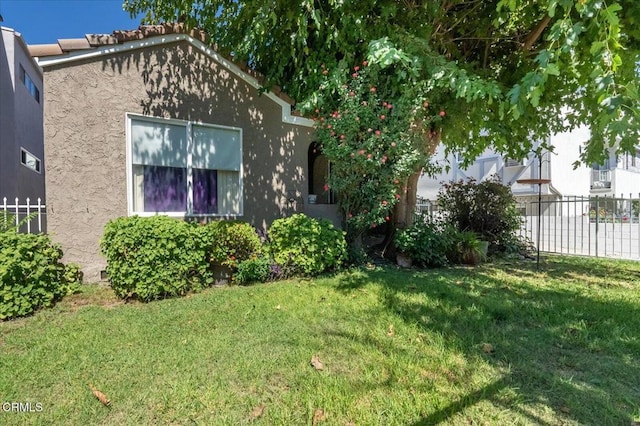 exterior space with stucco siding, a lawn, and fence