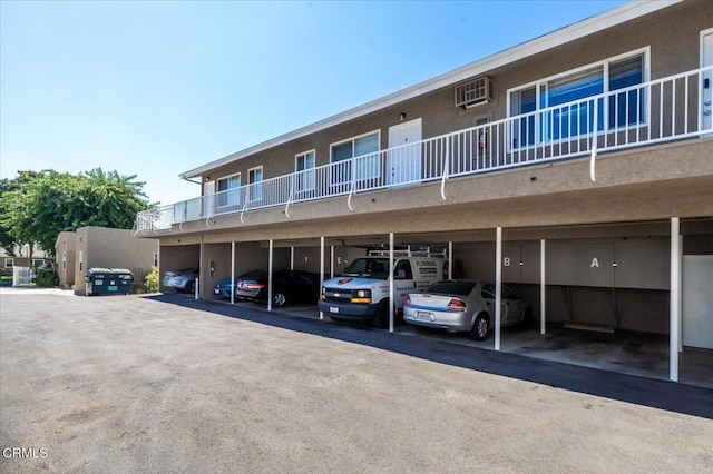 view of building exterior with covered parking and a wall mounted AC