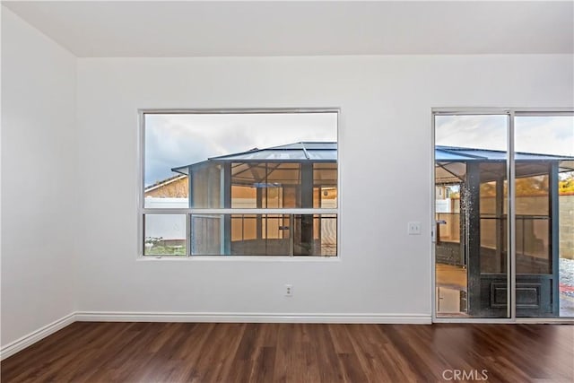 spare room with baseboards and wood finished floors