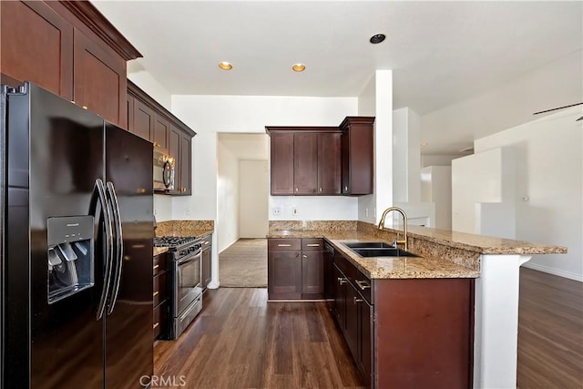 kitchen with a sink, appliances with stainless steel finishes, a peninsula, and dark wood finished floors