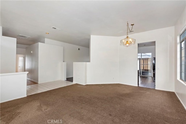 carpeted spare room with visible vents and a chandelier