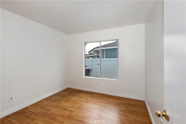 spare room with baseboards and wood finished floors