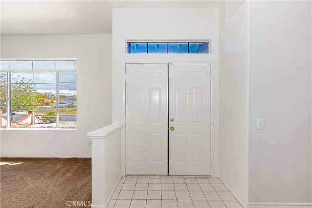 foyer with light tile patterned flooring, baseboards, and light carpet