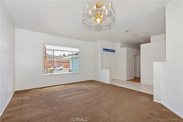 unfurnished room with a notable chandelier, visible vents, and carpet