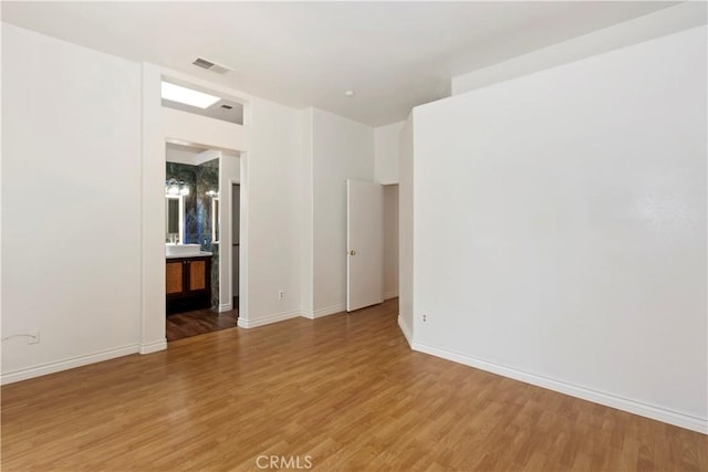 unfurnished room featuring baseboards, visible vents, and light wood finished floors