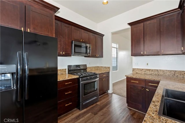 kitchen with dark brown cabinetry, light stone counters, appliances with stainless steel finishes, dark wood-style floors, and a sink