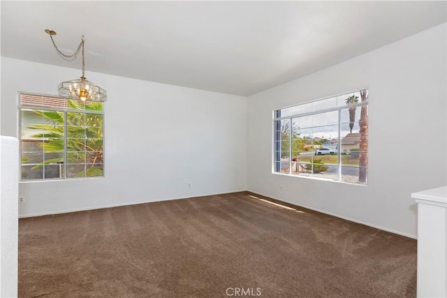 spare room featuring carpet and a chandelier