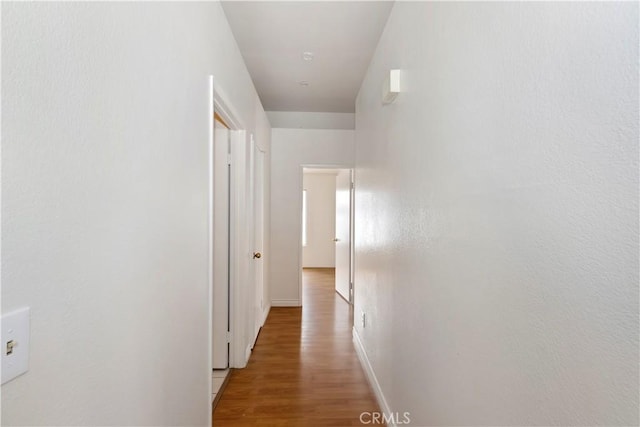 hallway featuring baseboards and light wood finished floors