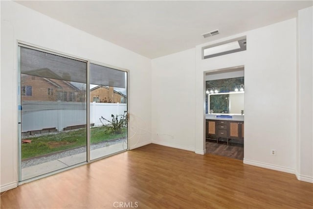 spare room with visible vents, baseboards, and wood finished floors