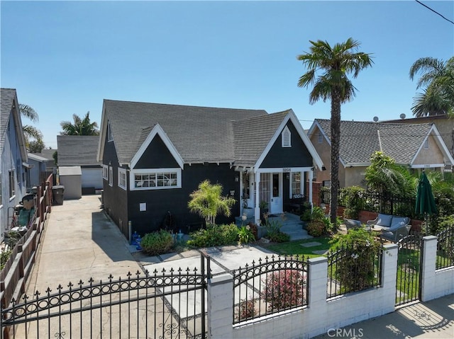 view of front of property featuring a fenced front yard, a shingled roof, and an outdoor structure