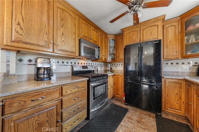 kitchen with stainless steel appliances, brown cabinets, glass insert cabinets, and a ceiling fan