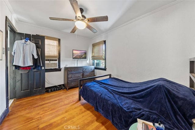 bedroom with ceiling fan, wood finished floors, and ornamental molding