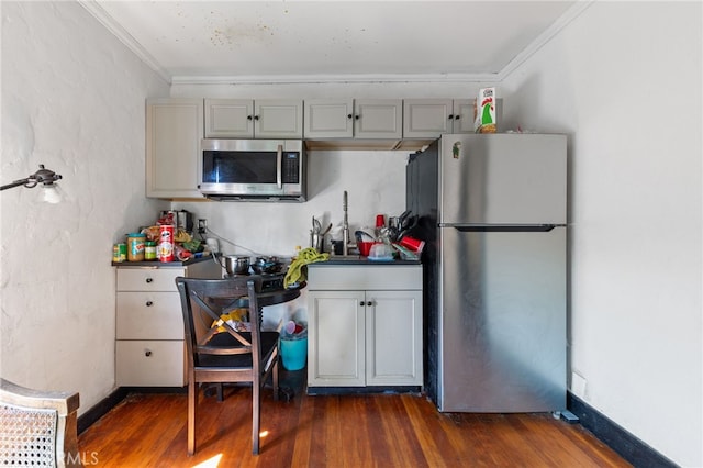 kitchen with gray cabinetry, dark wood-type flooring, baseboards, crown molding, and appliances with stainless steel finishes