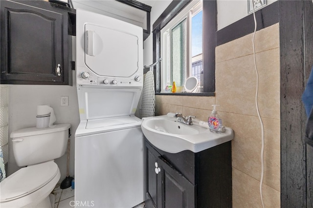 bathroom with toilet, stacked washer and clothes dryer, tile walls, decorative backsplash, and vanity