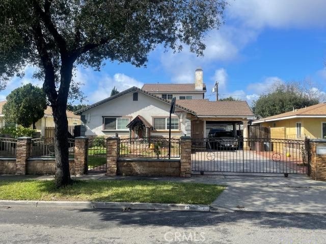 bungalow-style home with an attached carport, a fenced front yard, concrete driveway, a chimney, and a gate