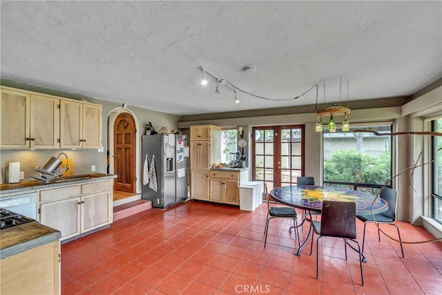 kitchen featuring a sink, stainless steel fridge, light brown cabinetry, and tile patterned flooring