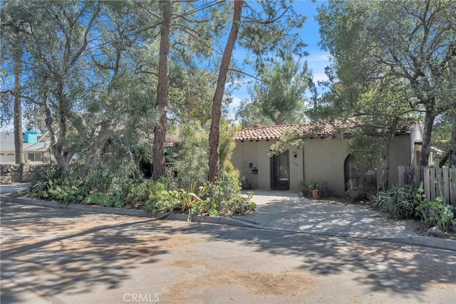 mediterranean / spanish home with stucco siding, fence, and a tiled roof