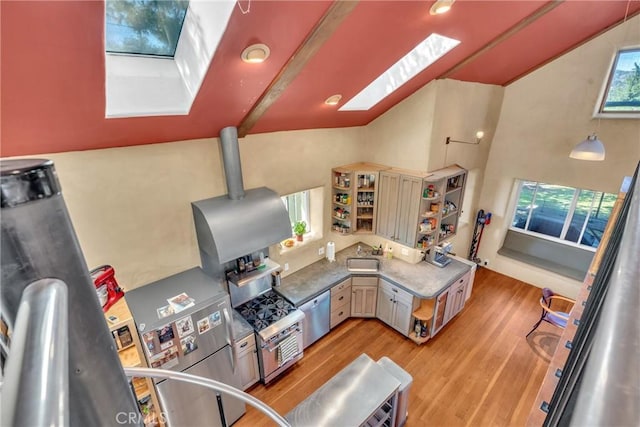 kitchen featuring open shelves, a sink, stainless steel appliances, a skylight, and light wood finished floors