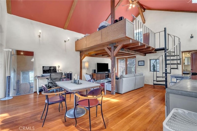 dining area with stairway, high vaulted ceiling, light wood-style flooring, ceiling fan, and beamed ceiling