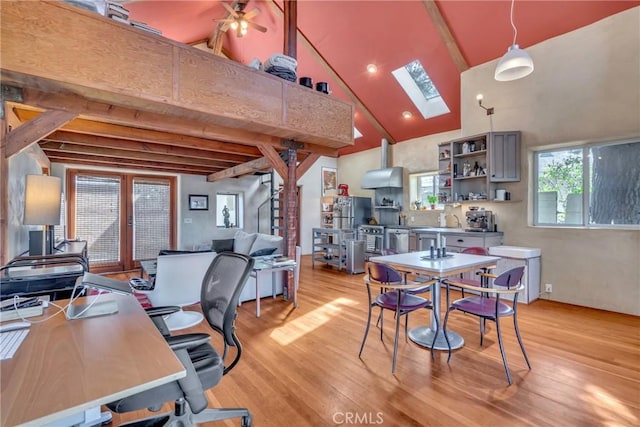 office space with ceiling fan, a skylight, light wood-style flooring, and high vaulted ceiling