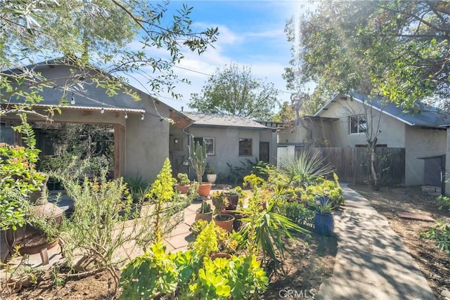 rear view of house featuring stucco siding and fence