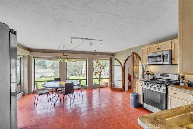 kitchen featuring tile patterned floors, light brown cabinets, a textured ceiling, stainless steel appliances, and light countertops