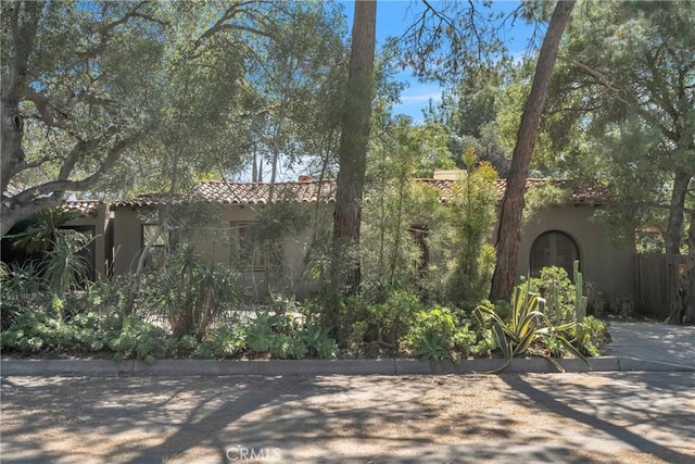 view of side of home featuring stucco siding, fence, and a tile roof